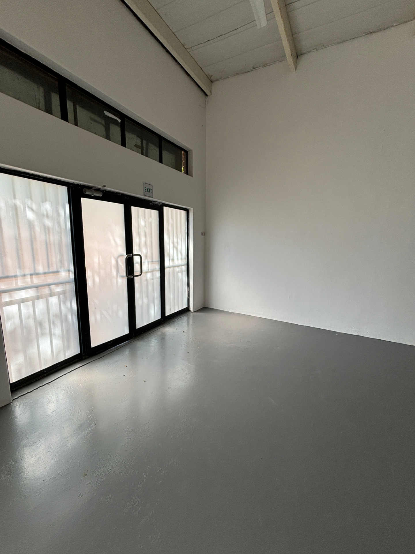 Commercial corner room with glass exit doors and exposed ceiling beams