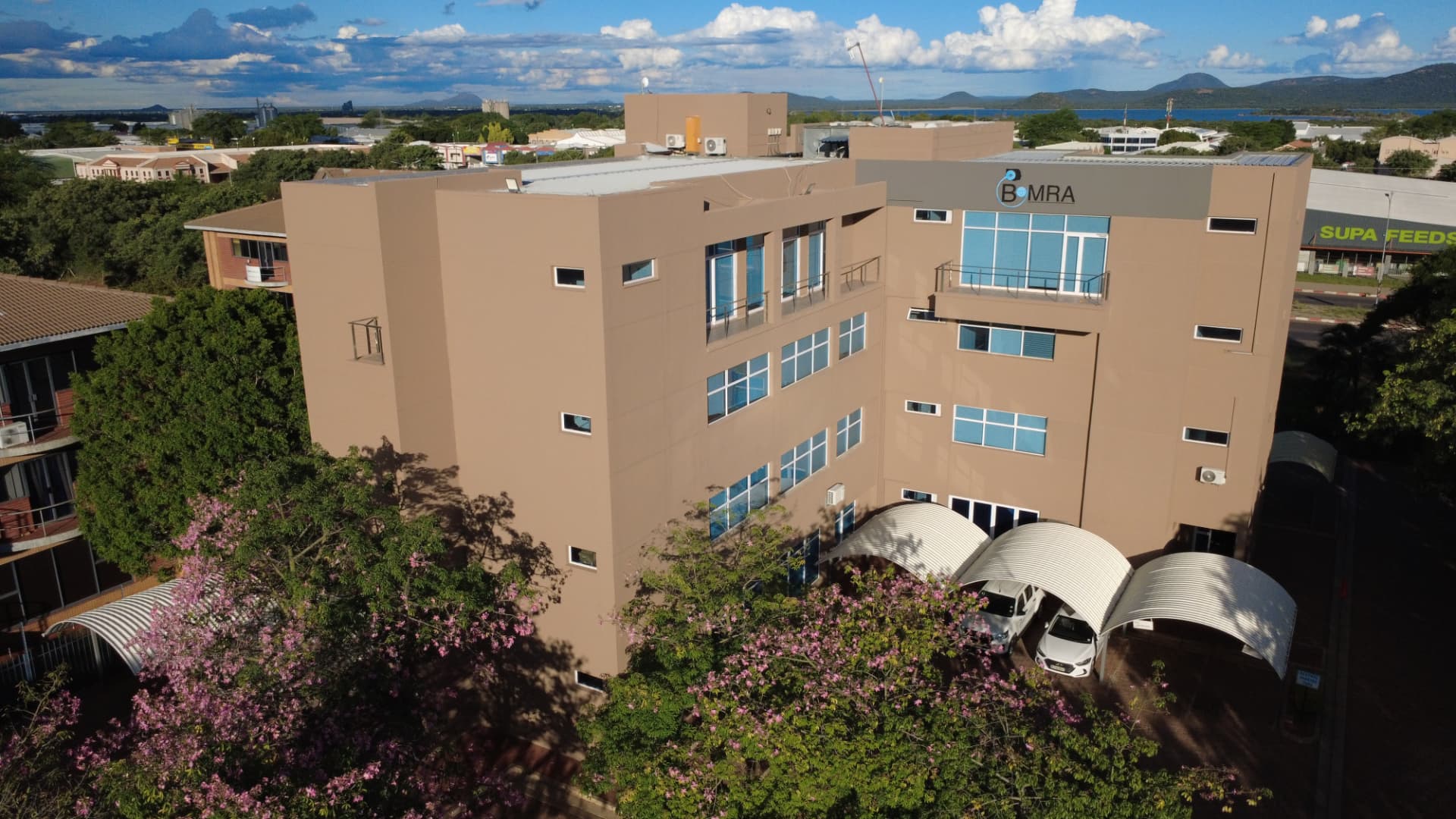 Aerial view of a four-storey commercial office building with carports and signage
