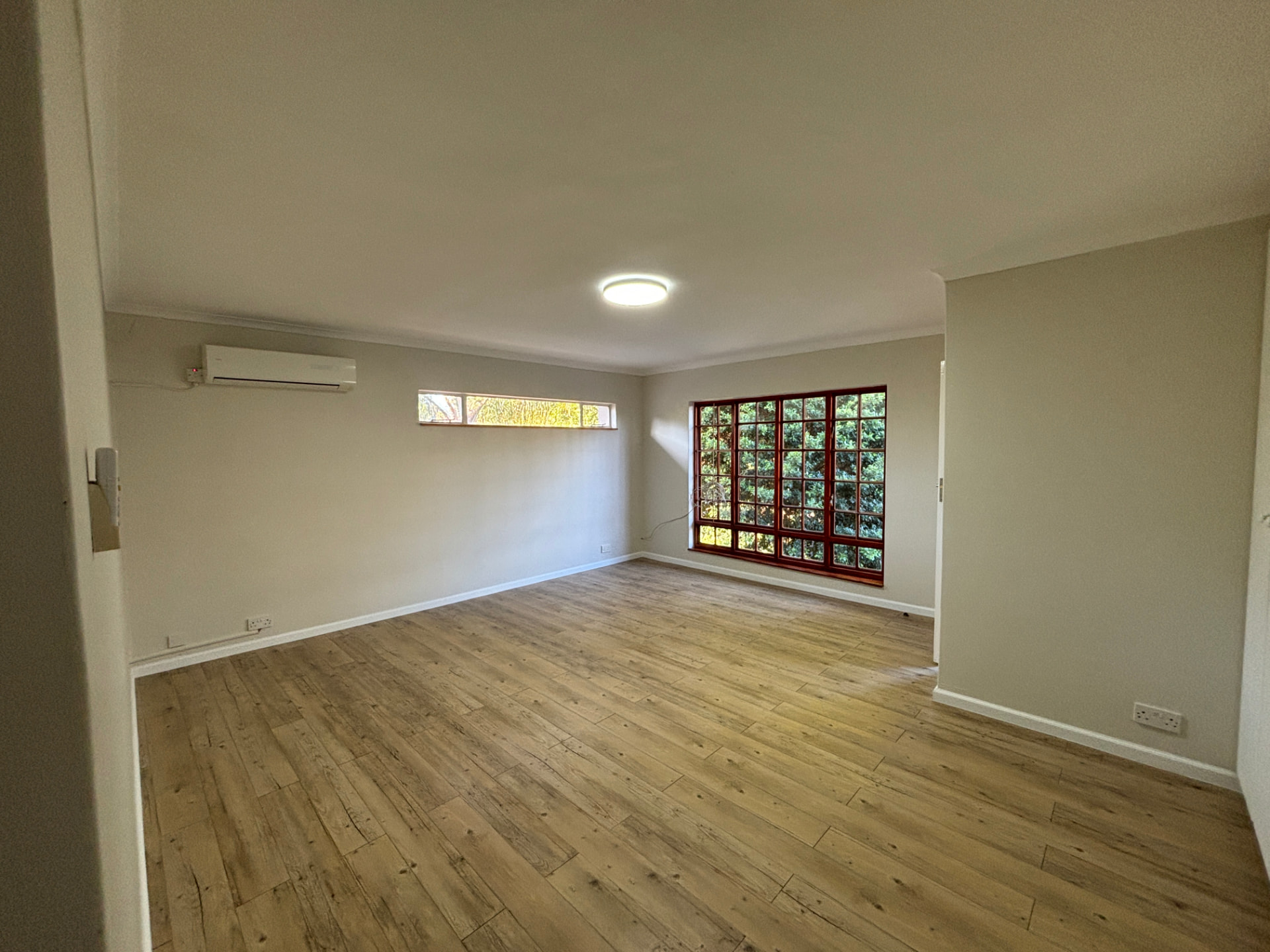 Repainted living room with new timber-look flooring and refurbished window frames