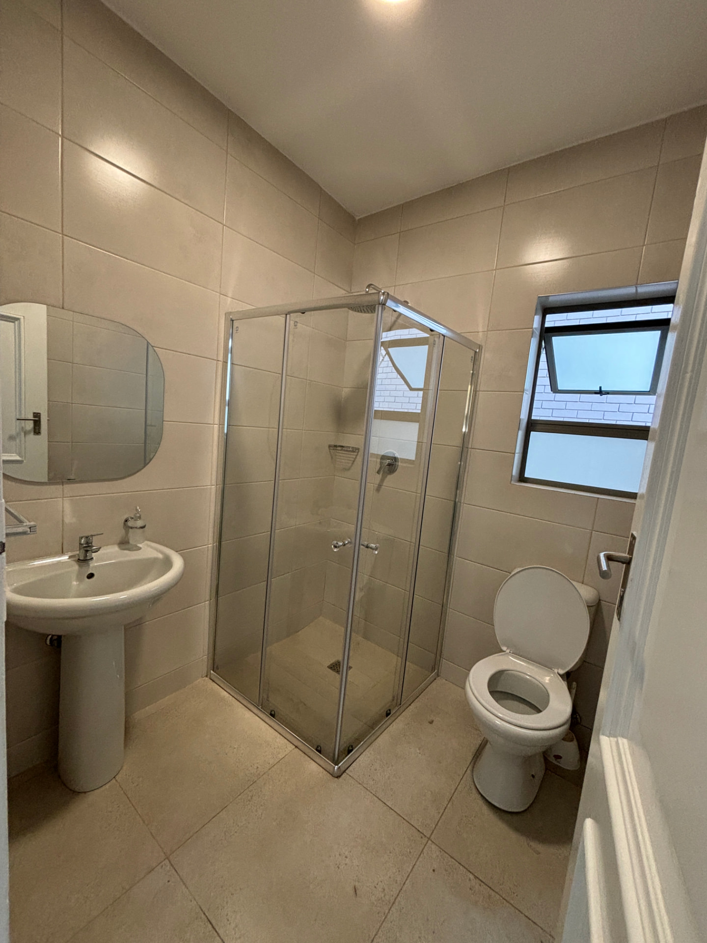 Renovated bathroom with tiled walls, corner shower enclosure and new sanitaryware