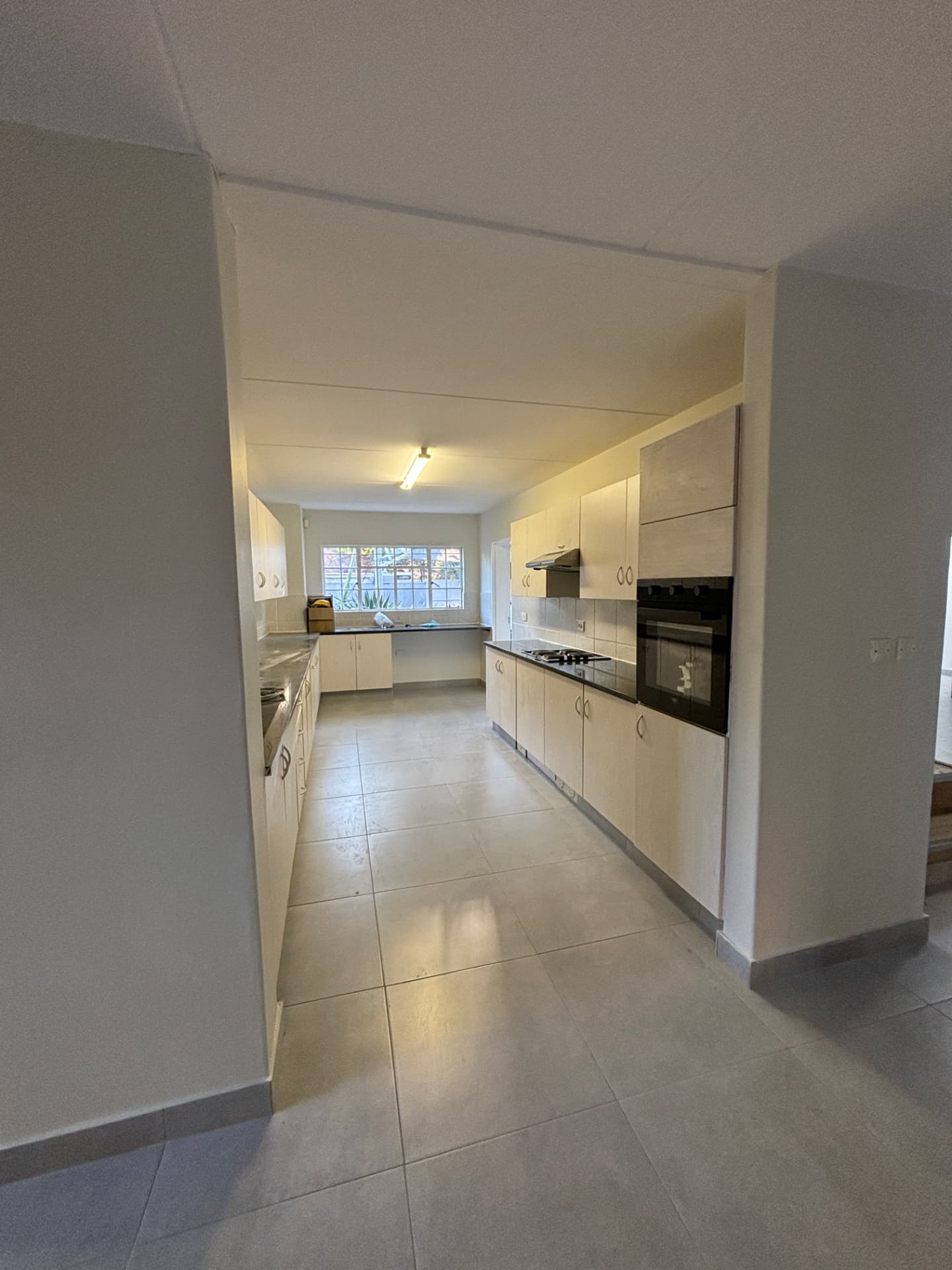 Refurbished galley kitchen with fitted cabinetry, oven and large-format floor tiles